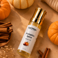 Pumpkin Spice body oil bottle with pumpkins, cinnamon sticks, and dried flowers on a brown background