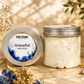 Body butter jar and tin labeled 'Soft Petalz Graceful' on a wooden surface with flowers.